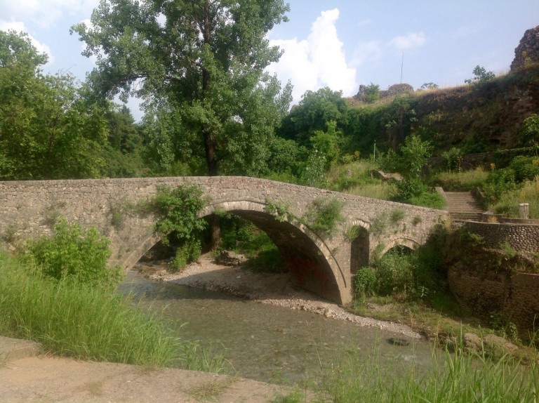 Vanha keskiaikainen kivisilta, jonka alapuolella pieni joki.