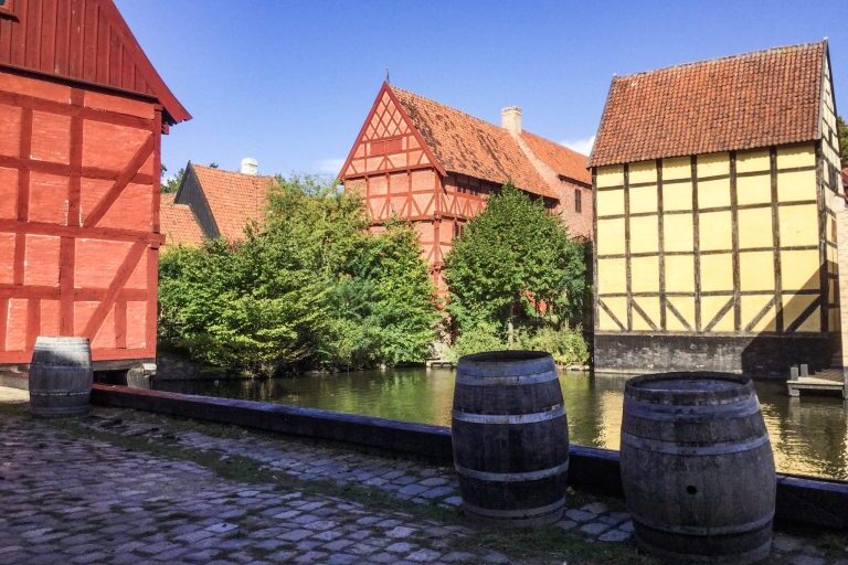 Punaisia ja keltaisia vanhoja taloja ja kaksi puista tynnyriä.