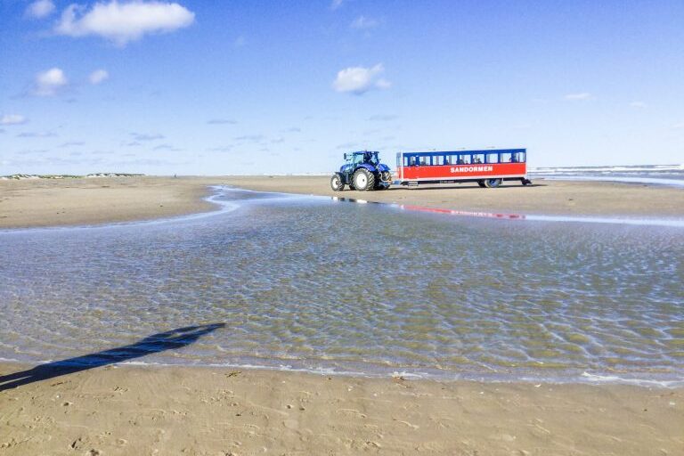 Traktori ja turisteja kuljettava kärri meren rannalla Tanskassa.