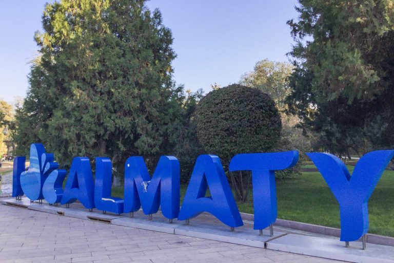 Siniset Almaty-kirjaimet puistossa.