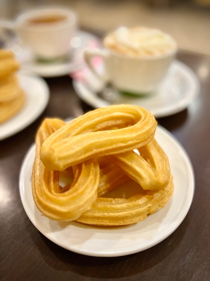 Churroja ja kahvikuppi ravintolapöydässä.