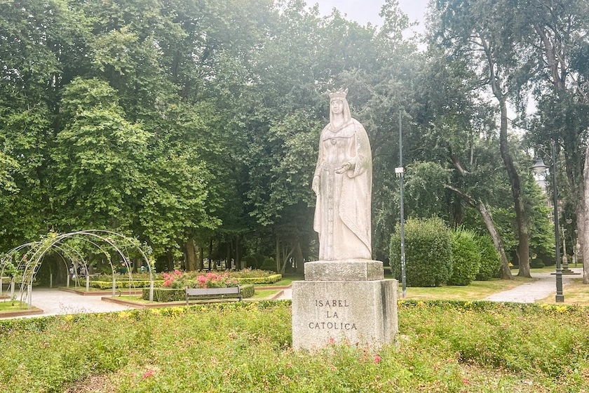 Gijónin kaupungin vaalea Isabel la Católica -patsas, taustalla puita.