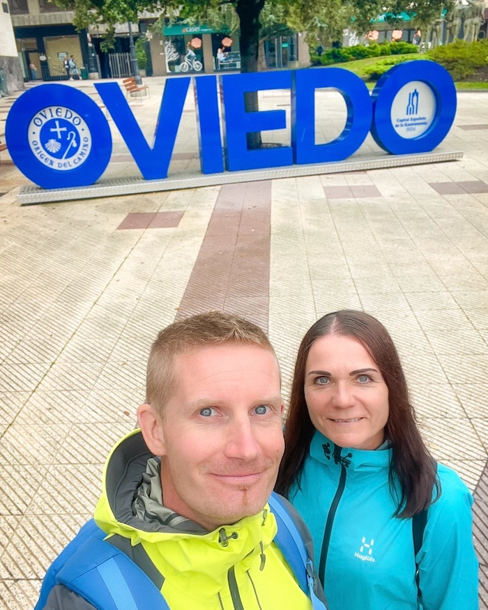 Suuri sininen Oviedo-kyltti, jonka edustalla on pariskunta.