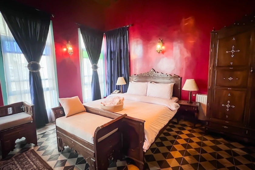 Hotellihuone, jossa punaiset seinät, parisänky ja valoja.