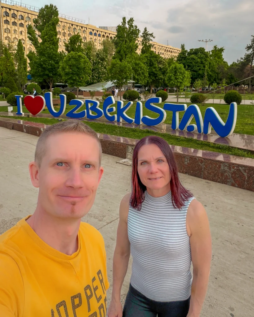 Kaksi turistia Uzbekistan-kyltin edessä.