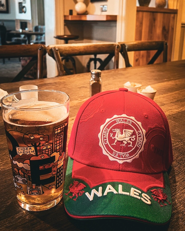 Siiderituoppi ja Wales-lippalakki pubin pöydällä